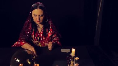 Çingene falcı mum ışığında masada beyaz taşlar hakkında merak ediyor. Ortalama planı
