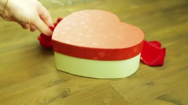 Kız gül yaprakları gelen ahşap bir masa üzerinde bir kalp ortaya konuyor. Zaman sukut. Yakın çekim