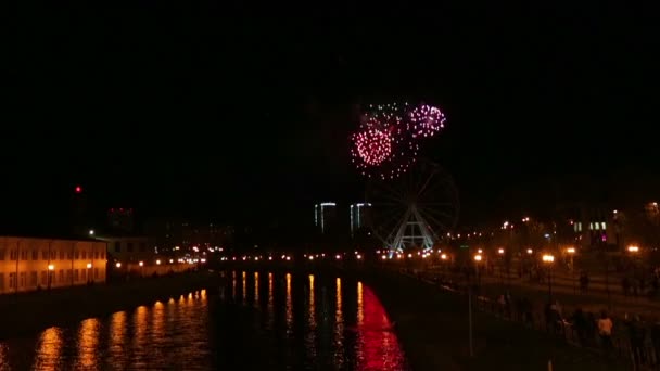 Heldere vuurwerk in de stad in de nachtelijke hemel weerspiegeld in de rivier — Stockvideo