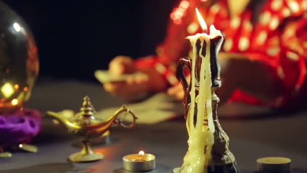 Brennende Kerze auf dem Tisch, hinter der sich die Zigeunerin auf den Karten wundert — Stockvideo