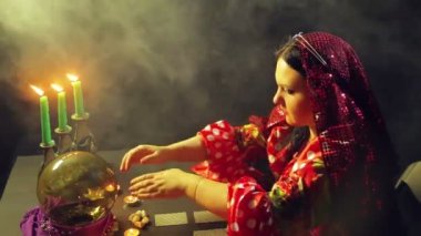 Mum ışığında bir masada kırmızı elbiseli Genç bir çingene topa gelecek okur. Ortalama planı