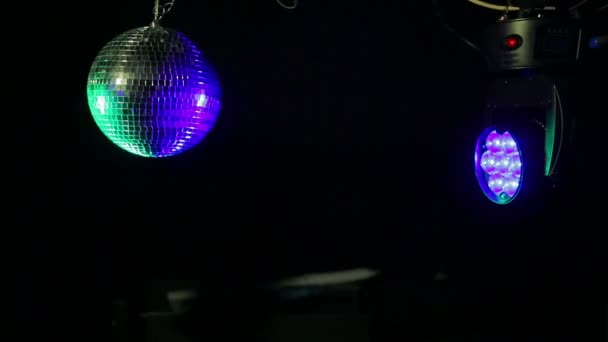 Mirror disco ball on a black background with blue and green searchlight beams directed at it — Stock Video