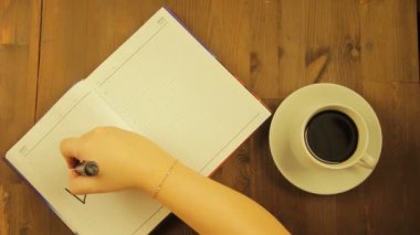 Kız siyah bir marker ile aşk kelime günlükte yazıyor ve kahve içer