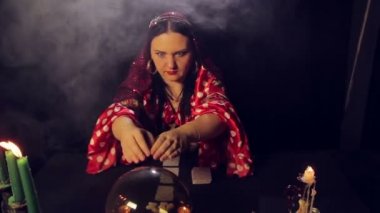 Sihirli bir kristal duman gelecekte bir çingene falcı mum ışığında bir masada okur.