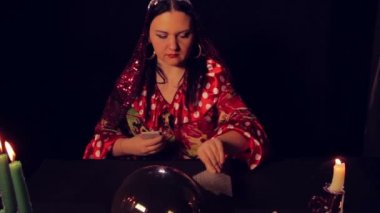Çingene falcı mum ışığında masada fortunetelling kartları yayılır.