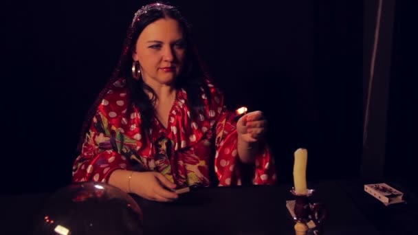 Gypsy spåkvinnan vid bordet spådom lyser ljus. Den genomsnittliga planen — Stockvideo
