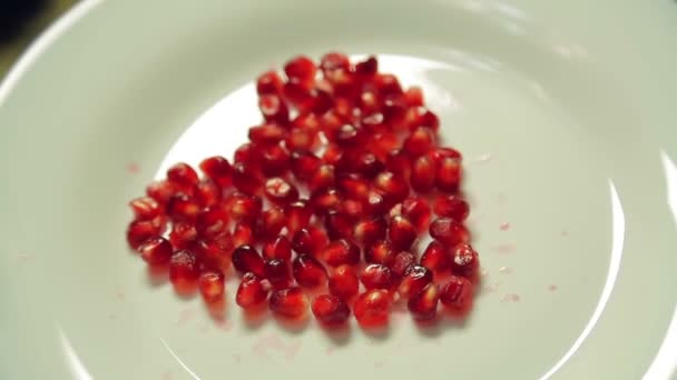 Corazón de semillas de granada en un plato blanco. Primer plano . — Vídeos de Stock