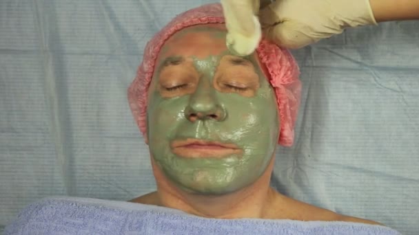 Руки косметолога снимают с лица человека маску из хлопка. — стоковое видео