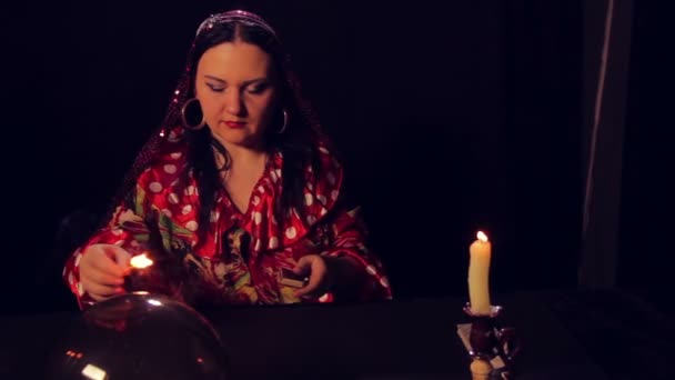 Gypsy fortune teller at the divination table lights candles. The average plan — Stock Video