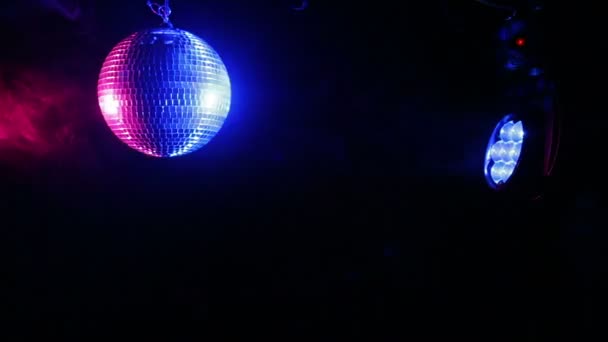 Дзеркальний диско-куля на чорному тлі з прожекторними променями різного кольору в диму . — стокове відео