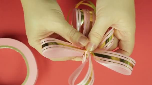 Las manos de mujer enderezan los pétalos del lazo de cinta de regalo de la cinta rosa — Vídeo de stock
