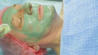 Kadın güzellik uzmanı bir adam s yüz pamuk pad ile tedavi edici çamurlar maske kaldırır.
