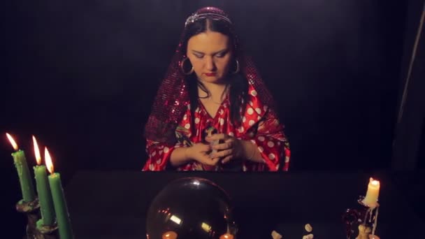 Gypsy fortune-teller at the table by candlelight wonders on the cards — Stock Video