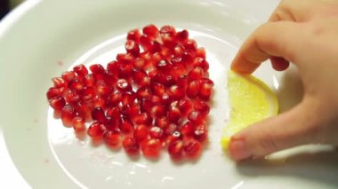 Nar taneleri beyaz tabakta kalbinde limon dilimleri ile dekore edilmiştir.