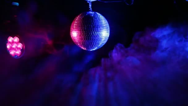 Spiegel disco bal op een zwarte achtergrond in de stralen van werkende verlichting en rook uit de rook machine — Stockvideo