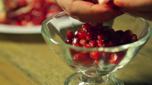 En kvinna separerar granatäpple kornen i en glasvas. — Stockvideo