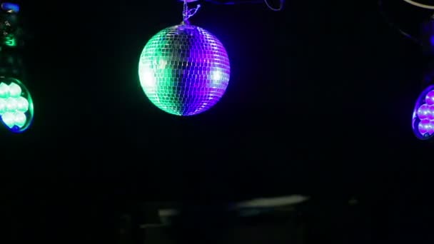 Spiegel disco bal op een zwarte achtergrond met de gestuurde balken van een zoeklicht in blauw en groen — Stockvideo
