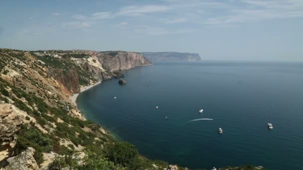 Cabo rodeado de montañas cubiertas de vegetación verde. Los yates navegan a lo largo de la costa. Vueltas de tiempo — Vídeos de Stock