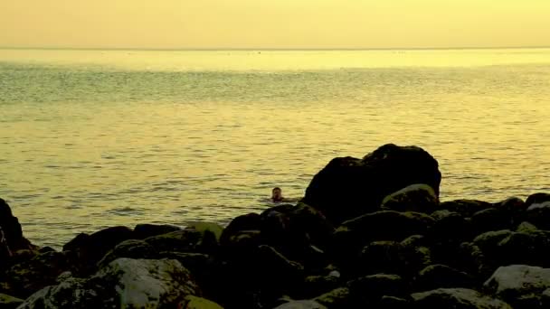 日落时, 一位年轻女子在海里游泳 — 图库视频影像