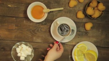 Bir kaşık ahşap bir masa üzerinde beyaz bir fincan çay ile karıştırarak el