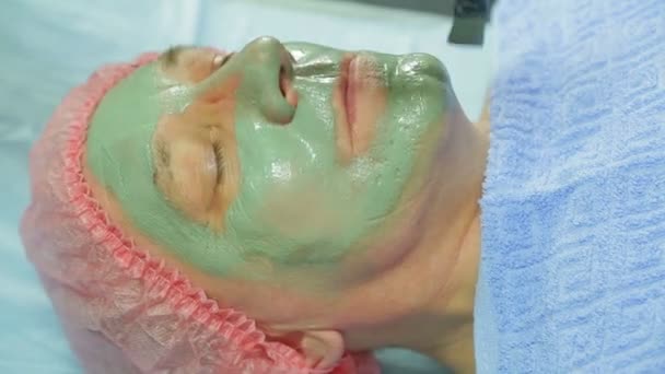 En kvinnlig kosmetolog gäller en helande lermask en mannen s ansikte med en borste. Sidovy. — Stockvideo