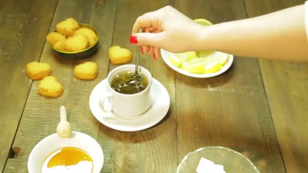 Una donna mescola tè verde appena preparato con un cucchiaio in una tazza bianca — Video Stock