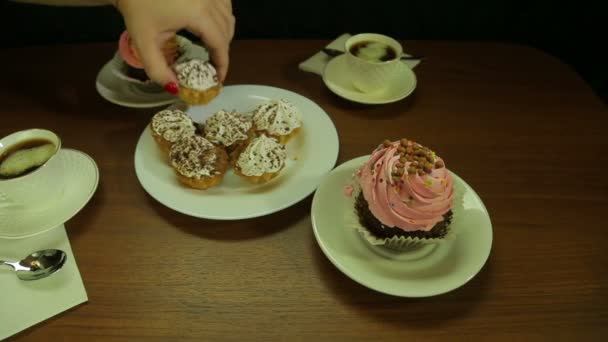 Ženská ruka dá dorty do bílé plotně na kávu. Průměrný plán — Stock video