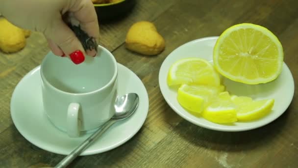 Weibliche Hand gießt schwarzen Tee in eine weiße Tasse — Stockvideo