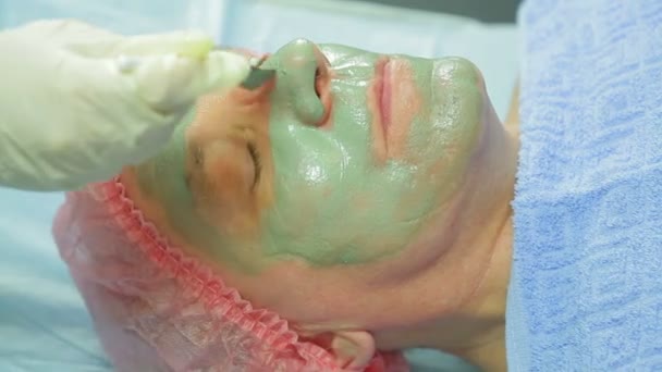 Una cosmetologa donna applica una maschera di fango al viso di un uomo con un pennello — Video Stock