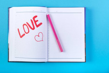Mavi bir arka plan üzerinde bir defter kalem kırmızı keçeli kelime aşık.