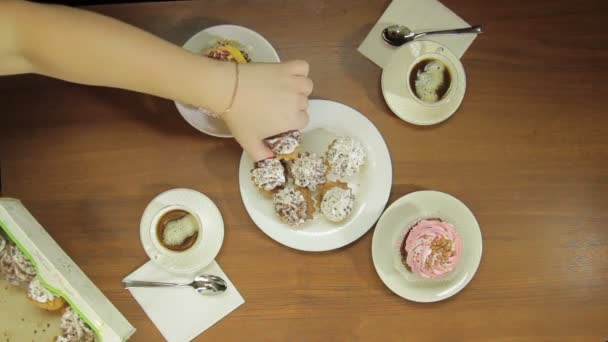 Vrouwelijke hand zet in een witte plaat cakes voor koffie — Stockvideo