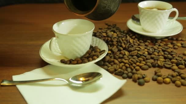 A woman pours coffee from the Turks in white cups and a scattering of coffee beans on the table — Stock Video