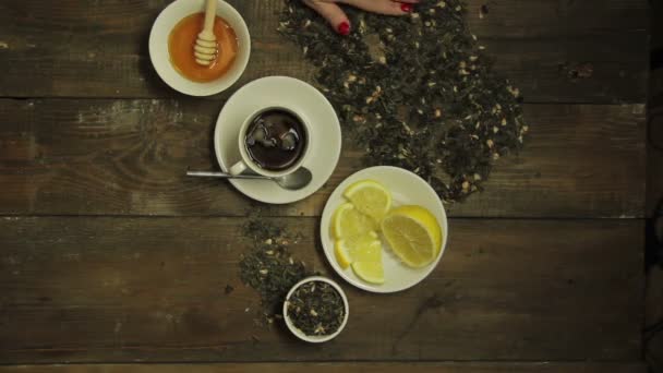 Femme verse du thé vert sur une table en bois à côté d'une tasse . — Video