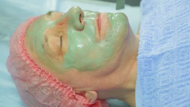 Een vrouwelijke schoonheidsspecialist geldt een genezende modder masker voor een man s gezicht met een borstel — Stockvideo