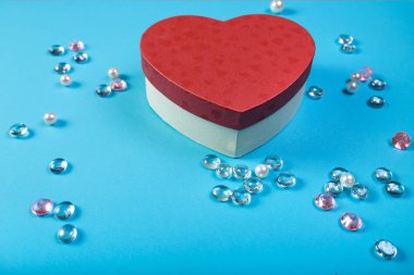 İle mavi bir arka plan üzerinde beyaz boncuk çerçevesinde bir kalp şeklinde Sevgililer günü için bir hediye kutusu.