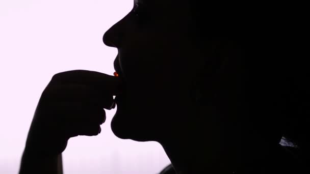 Silhouet van het hoofd van een vrouw die een boterham met rode kaviaar eet — Stockvideo