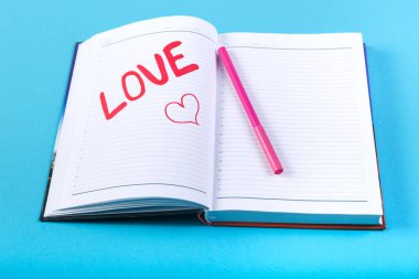 Mavi bir arka plan üzerinde bir defter kalem kırmızı keçeli kelime aşık.