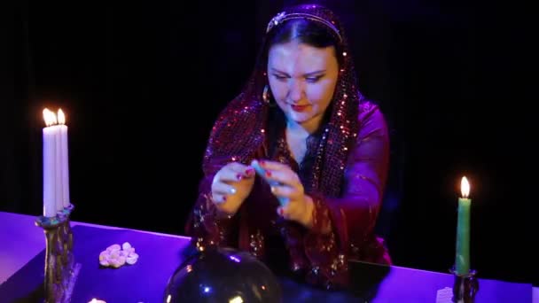 Nel magico salone a lume di candela, uno zingaro legge il futuro in una palla a specchio nel bagliore delle candele. — Video Stock