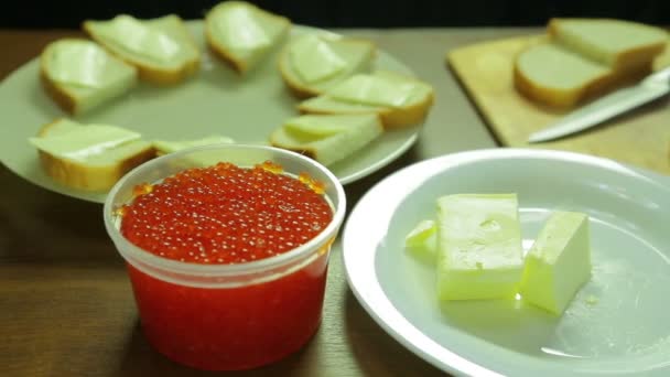 Caviar rojo en una lata y mantequilla en un plato blanco. Plan global — Vídeos de Stock