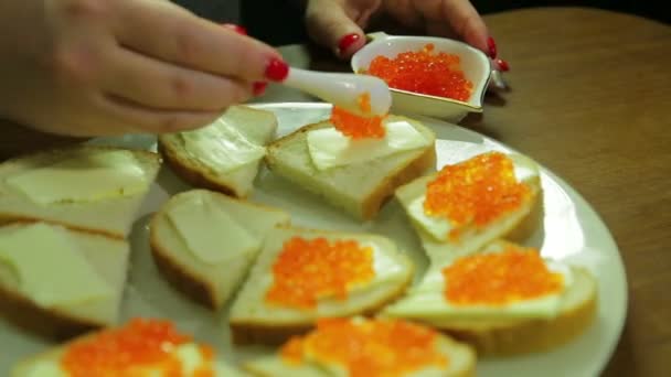 Eine Frau nimmt roten Kaviar aus einem Löffel iornitsa und verteilt Butter auf einem Canape mit Butte — Stockvideo