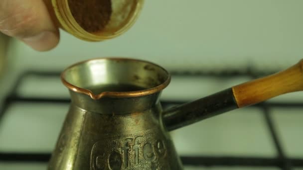 A mans hand pours ground coffee in a Turk. Close-up — Stock Video