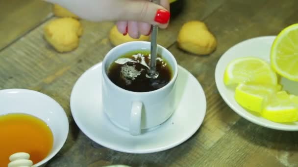 Frau rühren in Löffel in weißer Tasse auf Holztisch. frisch gebrühter schwarzer Tee. — Stockvideo
