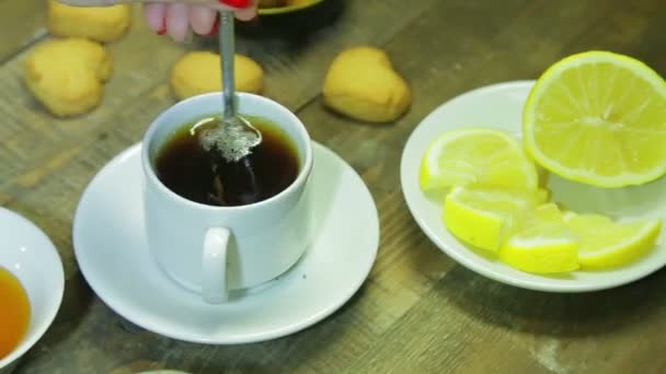 Femme mélanger dans la cuillère dans une tasse blanche sur une table en bois. Thé noir fraîchement infusé — Video