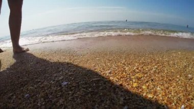 Kadın tabaklanmış bacaklarını ve deniz kıyı kenar waters boyunca yürüyüş