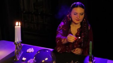 Kehanet salonda masada bir çingene bir kırmızı elbise ışık mumlar desenli bir şamdan