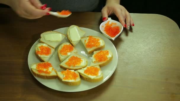 Una mujer toma caviar rojo de una cuchara de Iornitsa y extiende mantequilla sobre un canapé con mantequilla — Vídeos de Stock