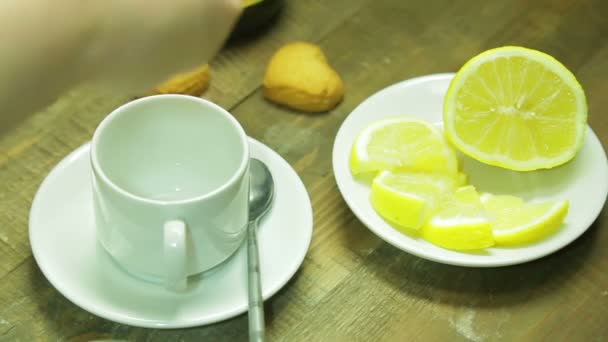 Vrouwelijke hand giet zwarte thee in een witte beker — Stockvideo