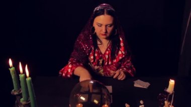 Çingene falcı mum ışığında masada kartlarında merak ediyor. Ortalama planı