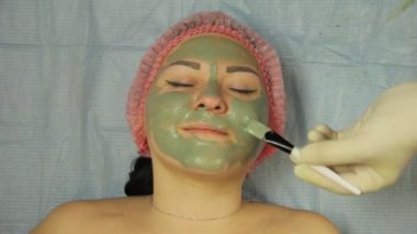 Eldiven giymiş bir erkek güzellik uzmanı bir çamur maskesi yüzünde özel bir fırça ile istemciler istemci koyar. Yakın çekim