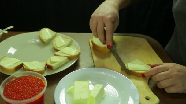 Une femme coupe du beurre sur du pain pour des canapés avec du caviar — Video